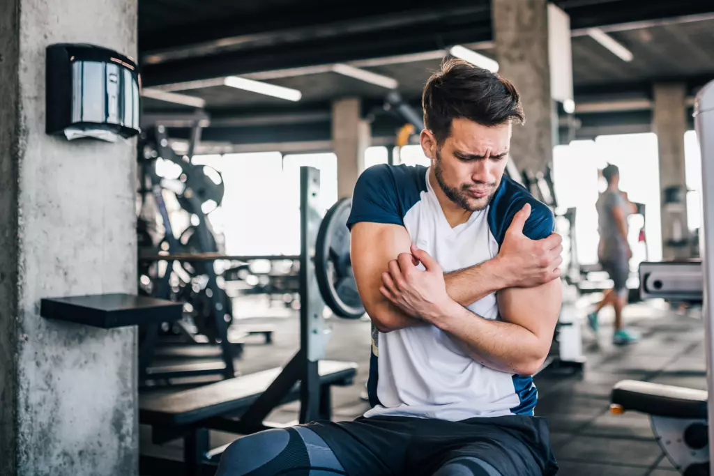 A man having pain in shoulder, possible rotator cuff injury sustained during heavy weight workout in Gym