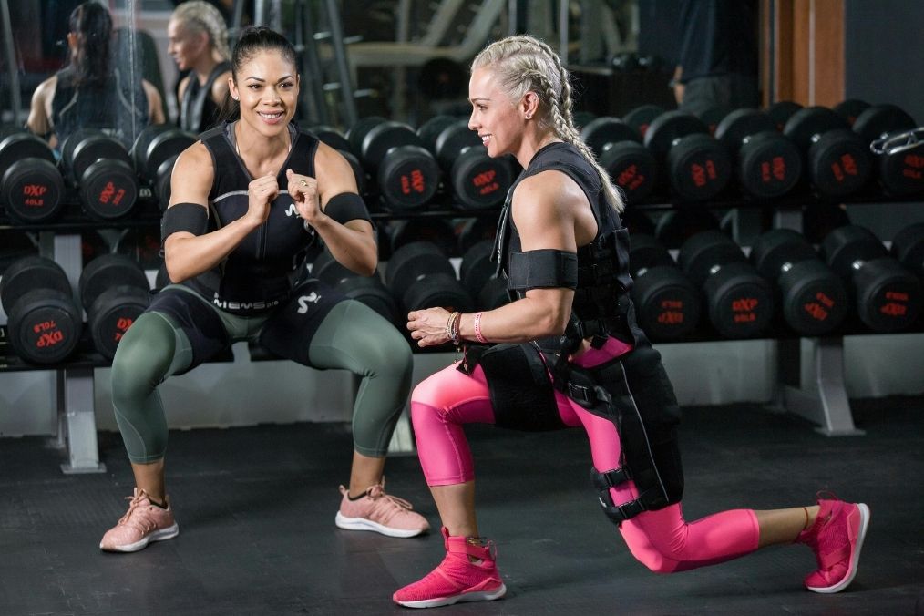 Women's doing barbell squat in modern gym, natural lighting, athletic wear
